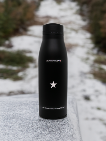 黒い絶縁ウォーターボトル、星マークと「DESIGNED IN USA」のテキスト、自然な背景。#ハイパフォーマンス